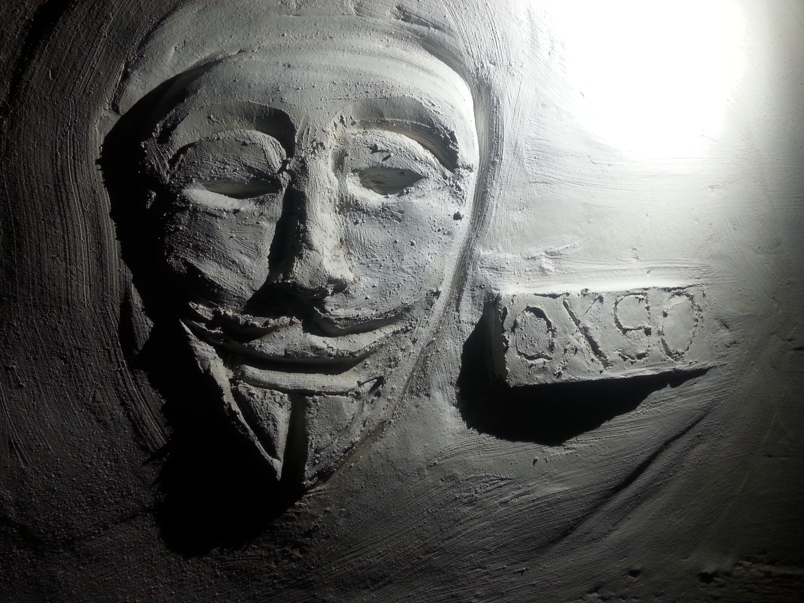 Eine Anonymous-Maske, aus Putz an eine Wand gemalt